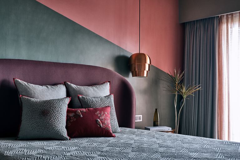 A bedroom diagonally painted charcoal grey and pink