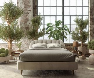 A bed surrounded by plants against an exposed brick wall.