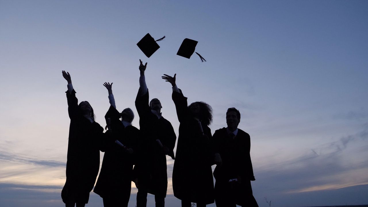 Graduates throw their caps into the air.