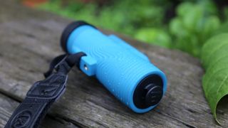 A blue monocular on a wood plank.