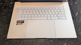 The Zenbook S 16 photographed on a dark marble surface with potted plants in the background.