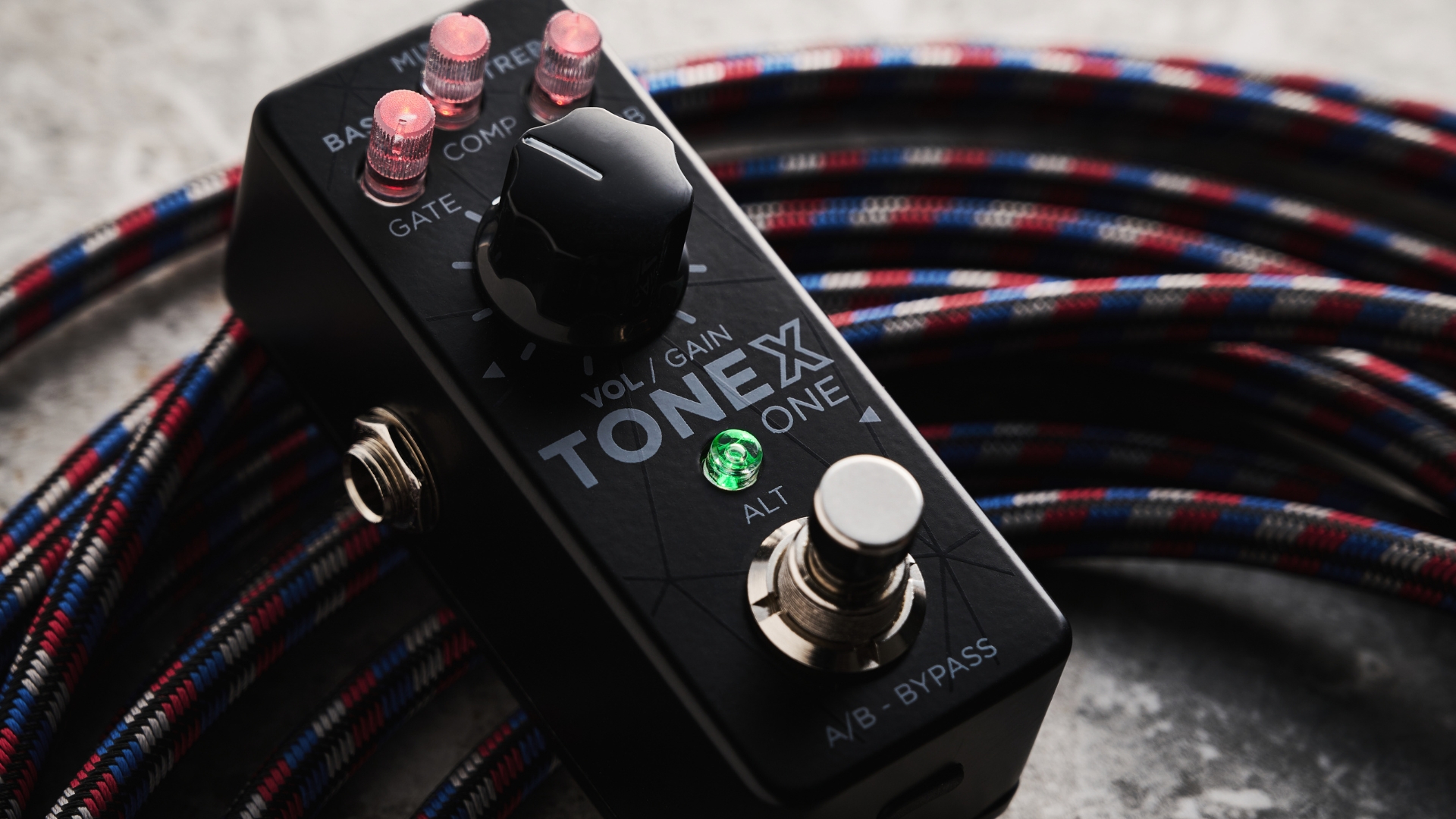 An IK Multimedia Tonex One pedal amp lying on a guitar cable