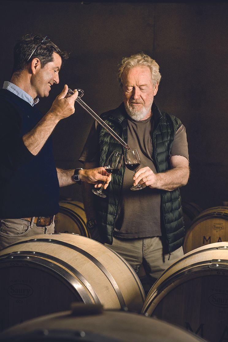 Two men sampling wine in a wine cellar