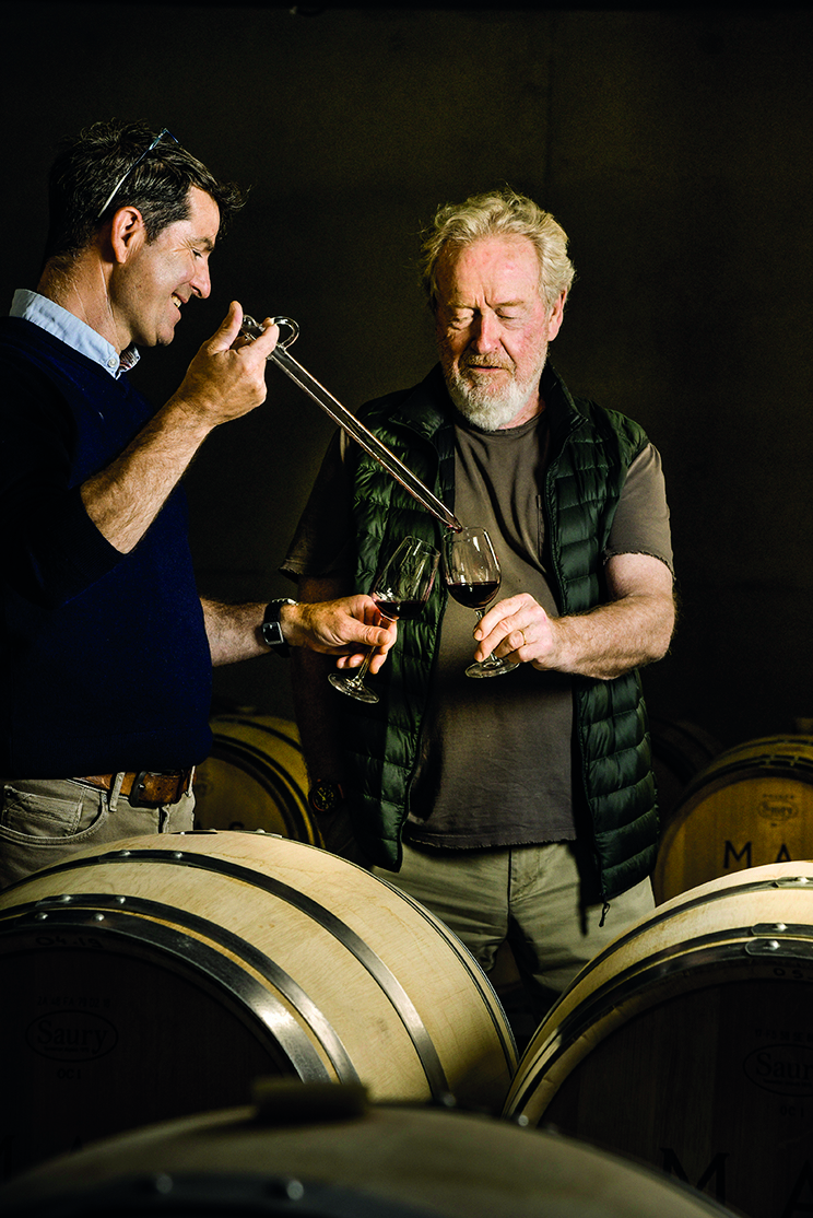 Two men sampling wine in a wine cellar