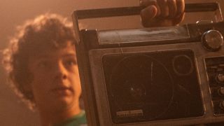 Noah Jupe holding up a stereo in A Quiet Place Part II