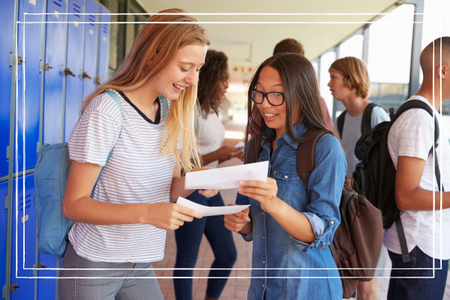 Happy teenage girls sharing exam results in school corridor 