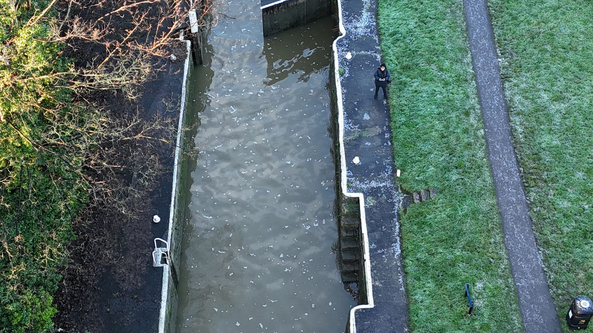 A photo of a person standing by a river taken on a DJI Flip drone