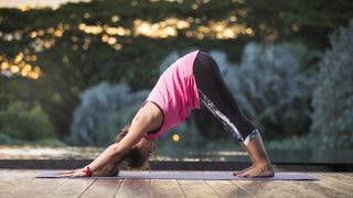 woman doing downward dog yoga at sunset