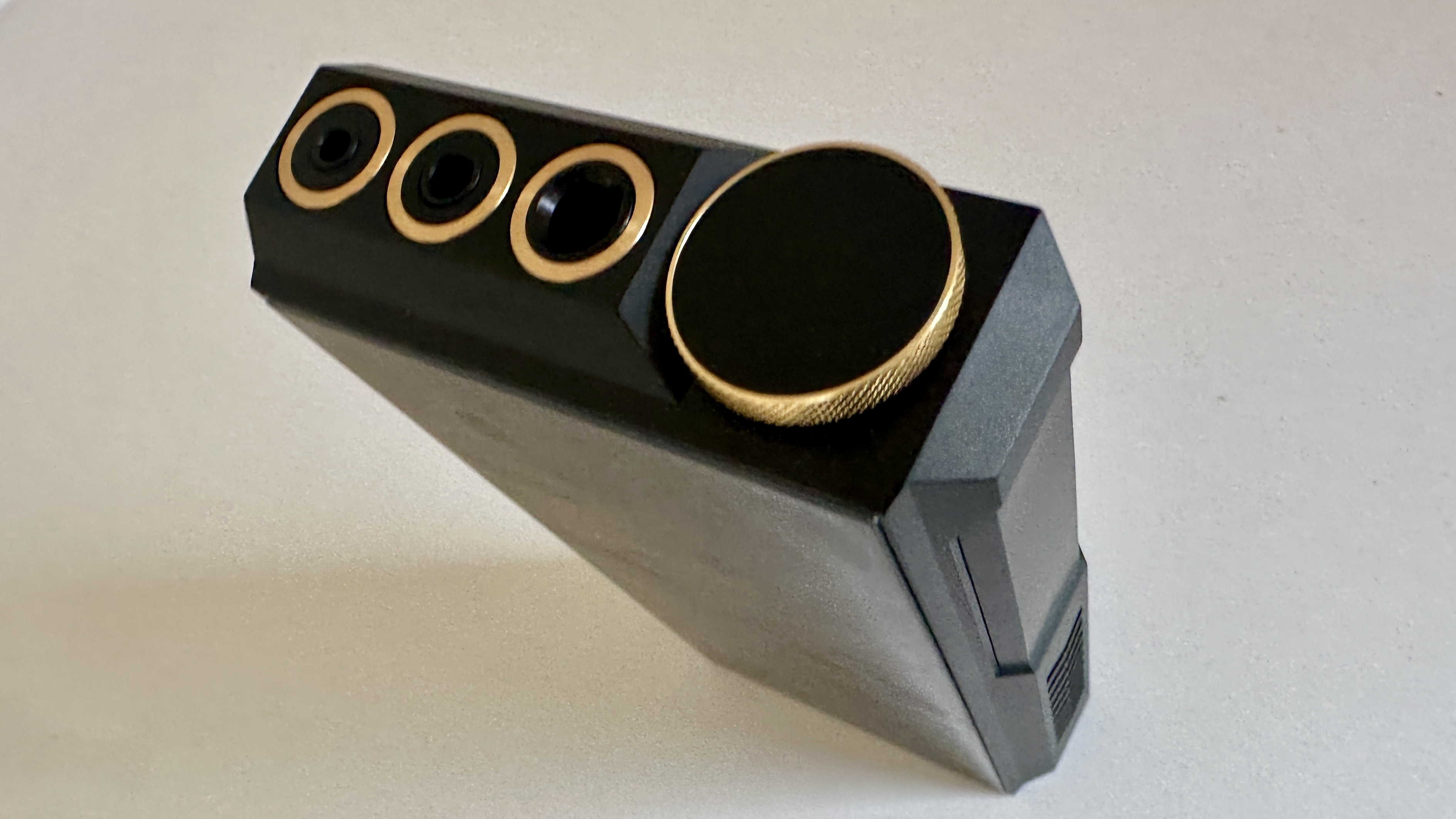 The FiiO M27 player with screen and dial showing, and content on the screen, on beige or yellow background