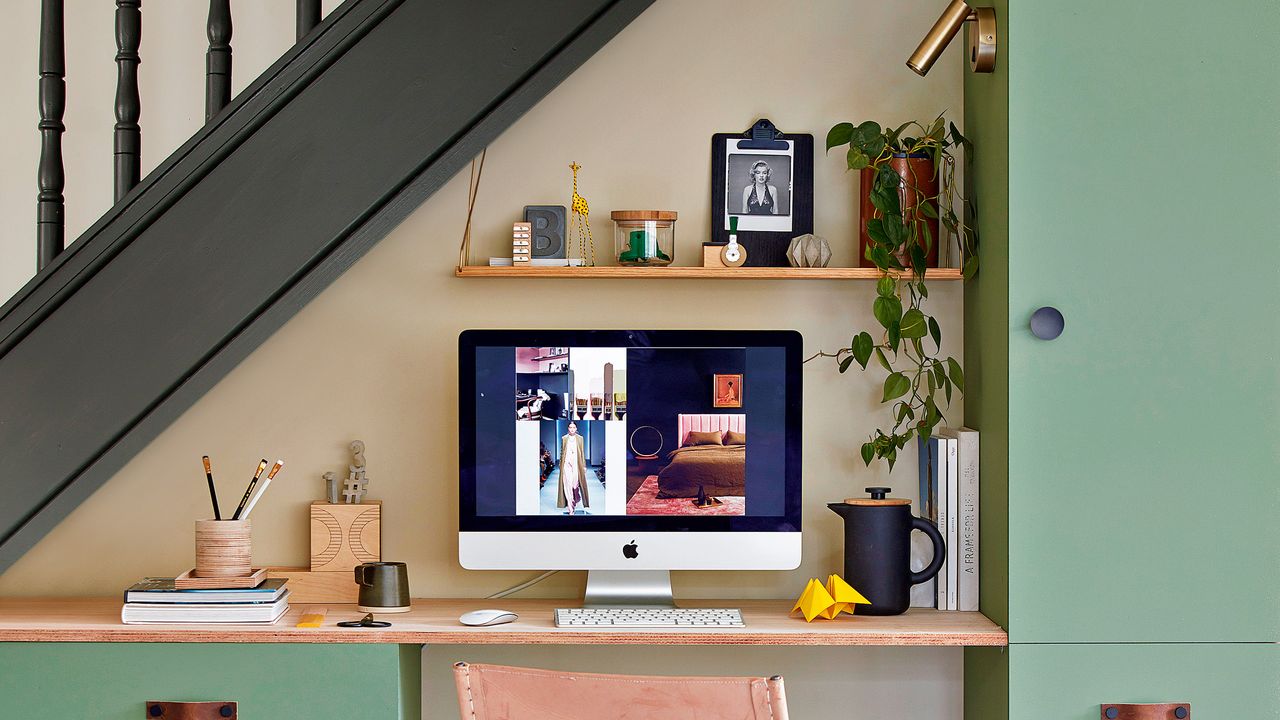 home office space in the alcove of the under stairs space with a laptop open on the desk