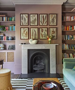 A pink room with two floor-to-ceiling full bookshelves and a fireplace behind a seating arrangement