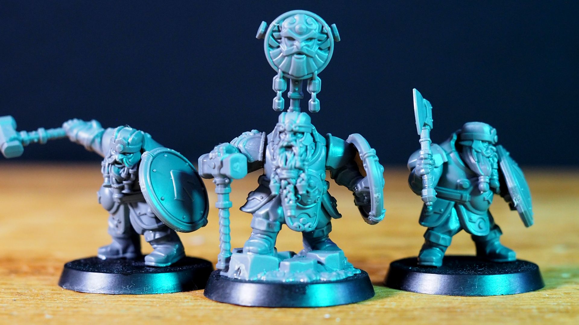 Khazalite Holds dwarves lined up on a wooden surface, against a dark background