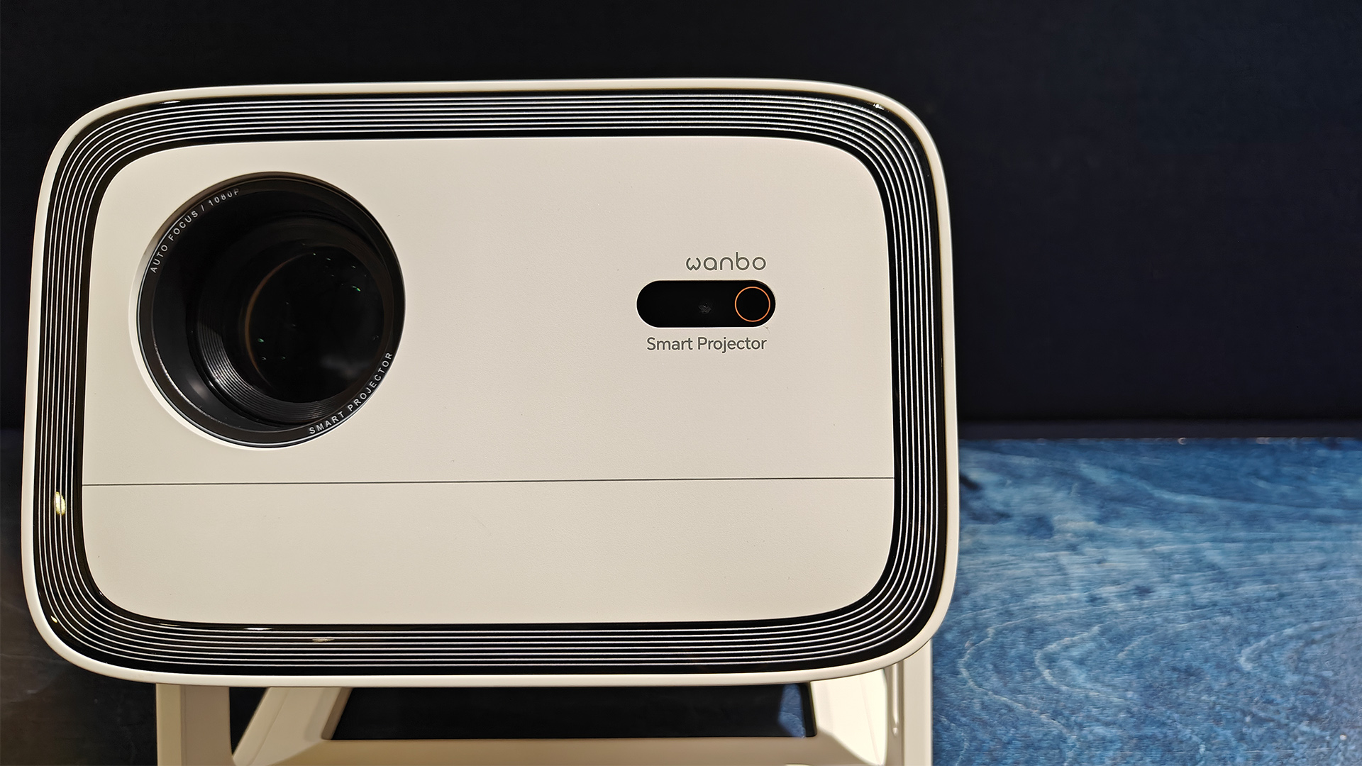 Wanbo Vali 1 home cinema projector close up on 'face' of projector showing lens and Wanbo logo