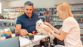 Man paying for something at pet shop with dog