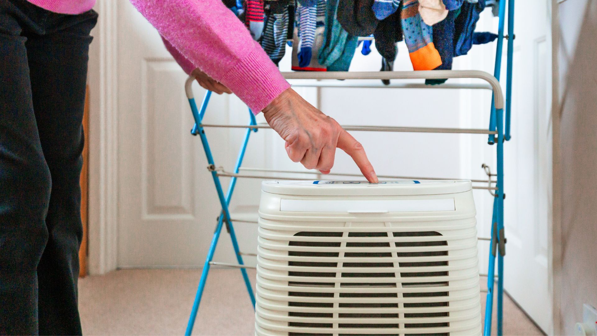 picture of woman adjusting settings on dehumidifier drying clothes