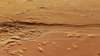 a deep, ragged trench carved into a reddish-orange landscape