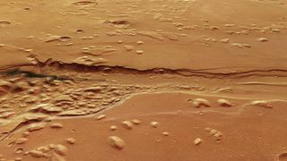 a deep, ragged trench carved into a reddish-orange landscape