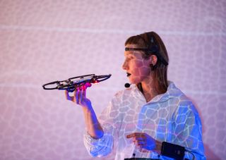 Woman holding a drone with patterned light shining on her