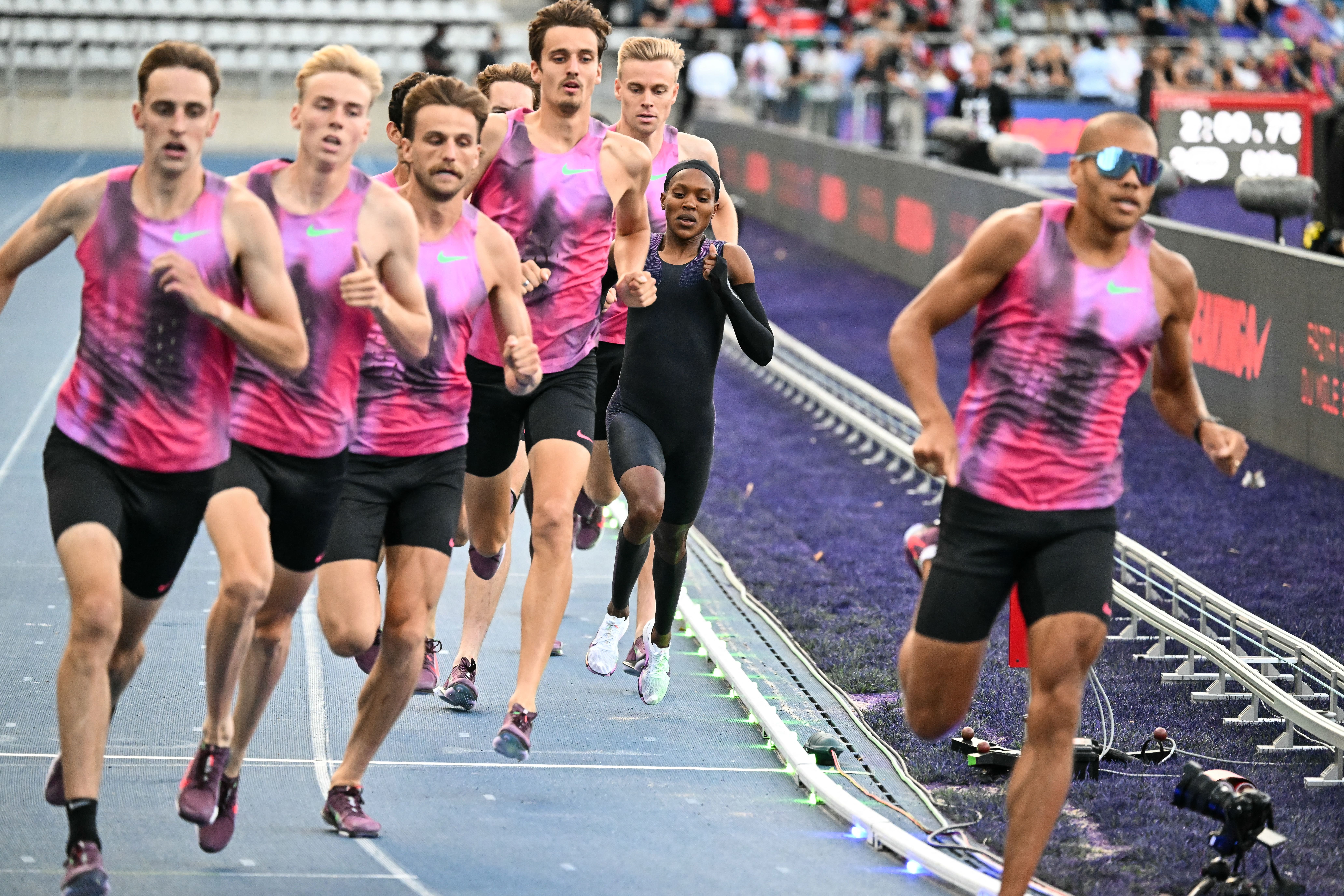 Faith Kipyegon runs behind a formation of male pacemakers in matching pink and black Nike kits during her historic mile attempt at Paris’ Stade Charléty.
