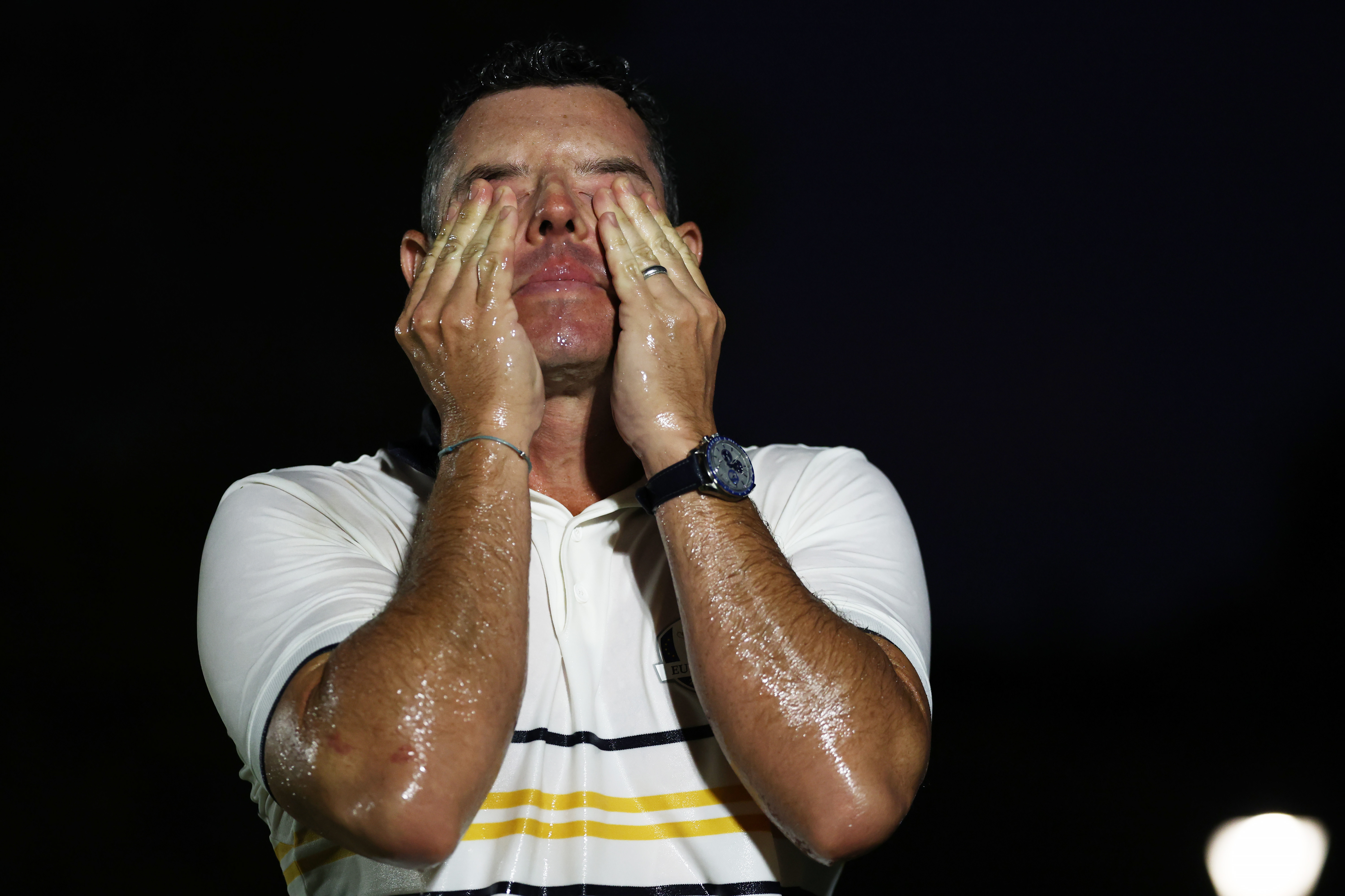 Rory McIlroy puts his hands to his face after being soaked in champagne following Team Europe&#039;s Ryder Cup win