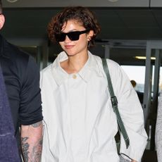 Zendaya wearing a The Row trench, skirt, and loafers at JFK airport