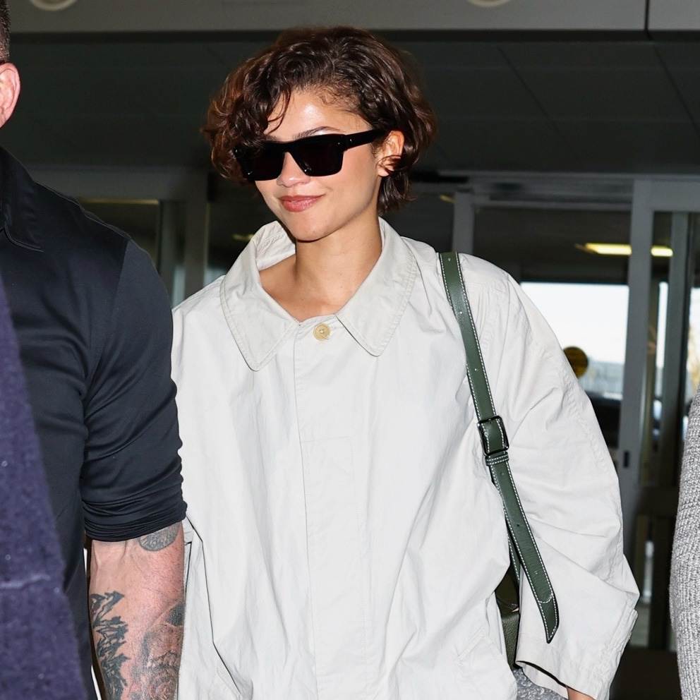 Zendaya wearing a The Row trench, skirt, and loafers at JFK airport