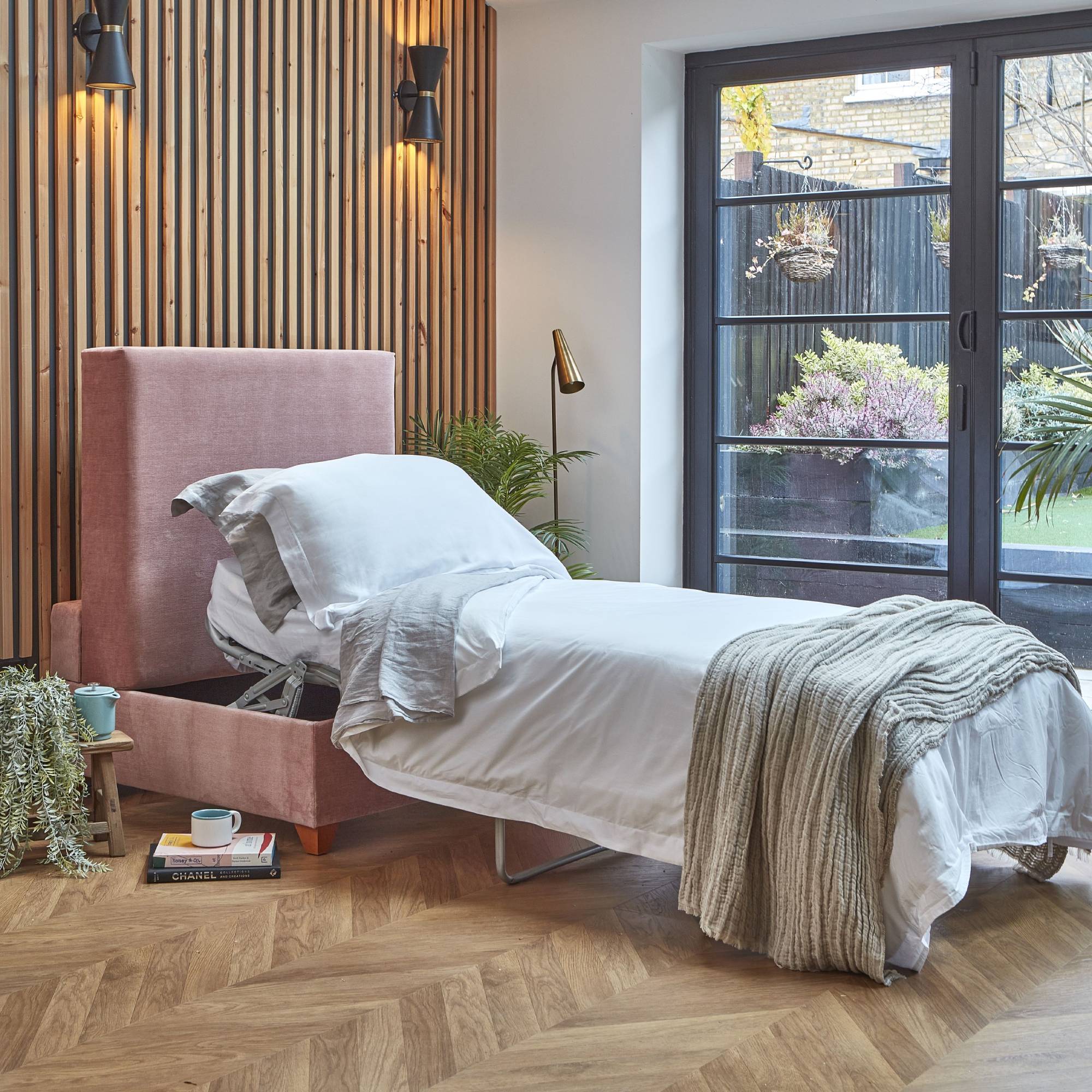 pink pull out single bed against wood panelled wall in modern bedroom