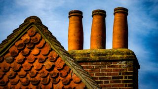 masonry chimney stack with three pots on old house