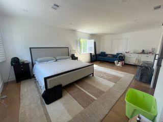 A bedroom with white walls, a large beige carpet and a bed