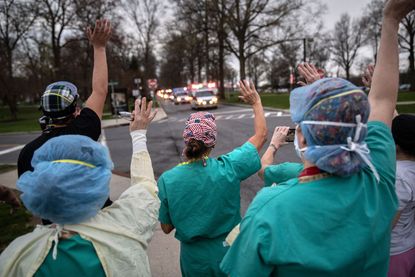Health care workers wave to ambulances outside New York City.