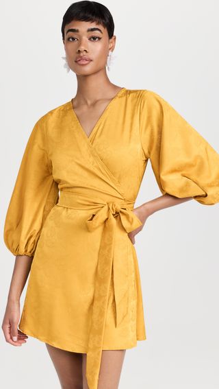 a model wears a short wrap dress in mustard yellow