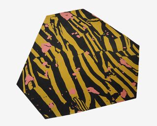 A rug by Cody Hoyt. Asymmetrical, leopard print-like rug, in shades of yellow and black, with pink blobs of color throughout.