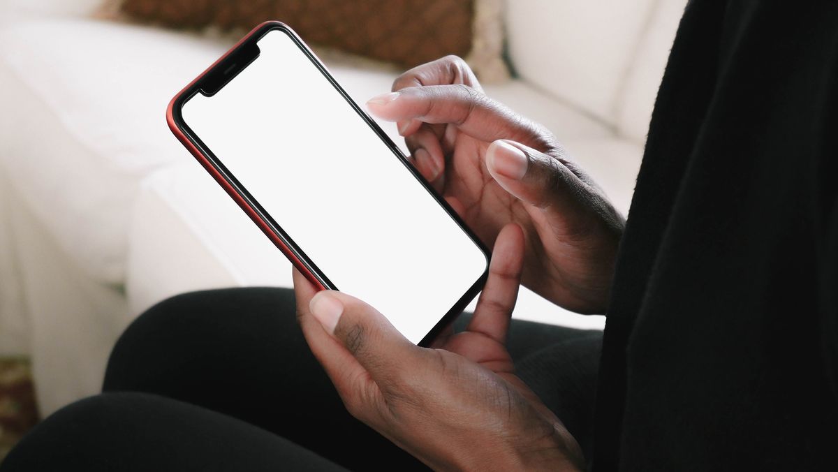 A woman holding a smart phone while sitting on a sofa