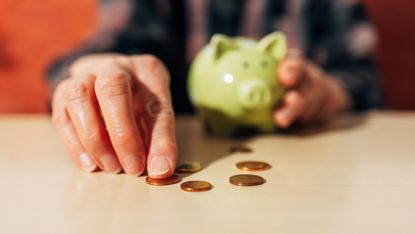 A close up of a senior man's hands as he counts pennies from his piggy bank.
