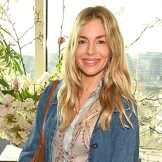 Sienna Miller wearing a floral blouse and denim jacket at an event