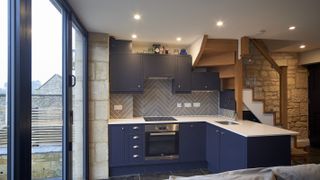 small blue kitchen with white worktops