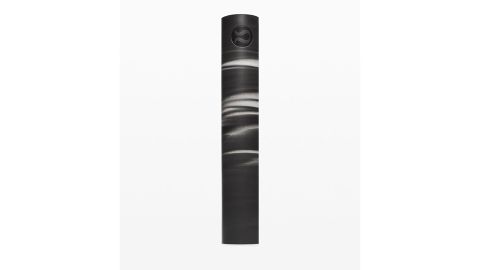 Images shows a black rolled up Lululemon Reversible 5mm Yoga Mat against a white background.