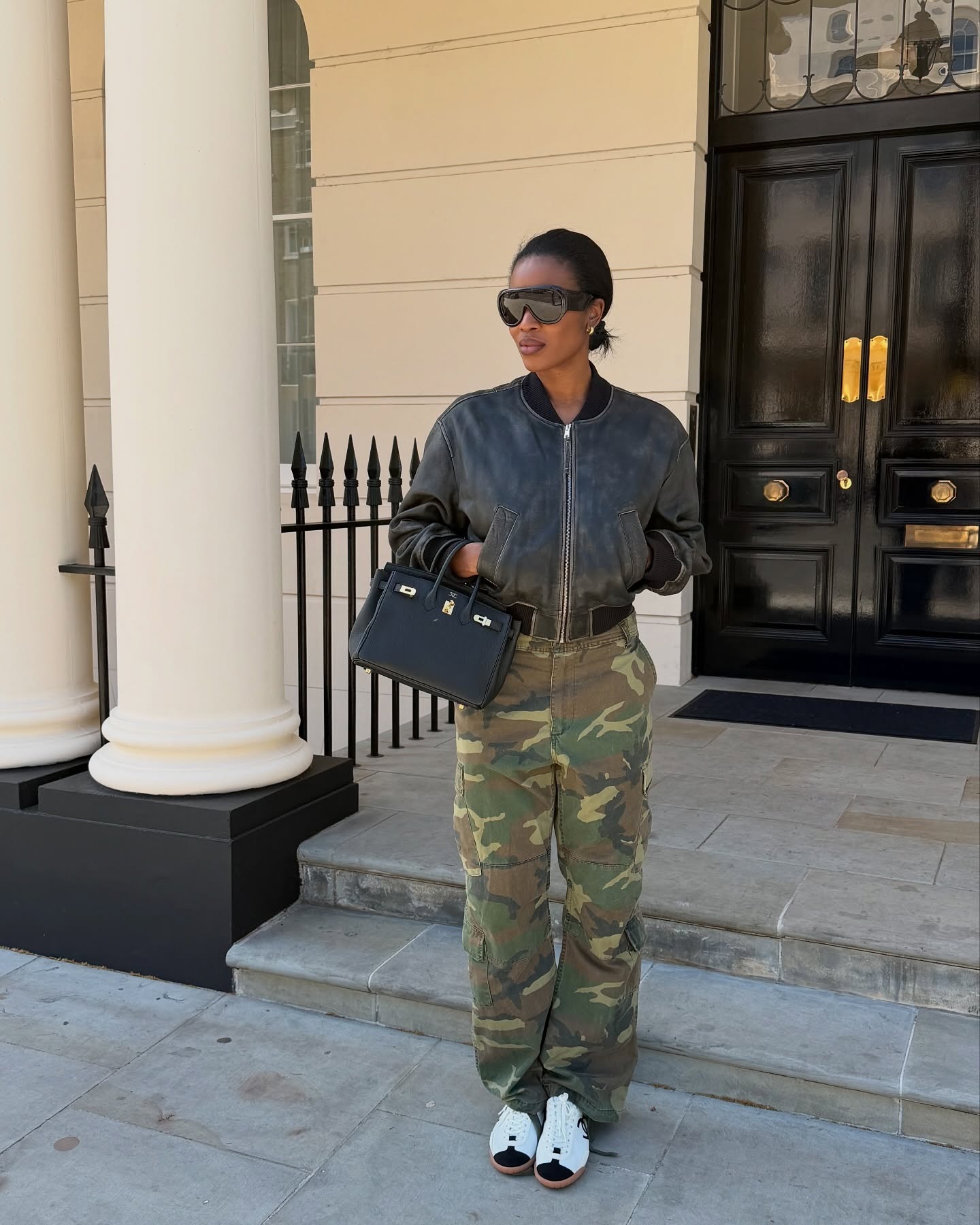 Influencer wearing a leather bomber jacket, camo pants, and Chanel sneakers