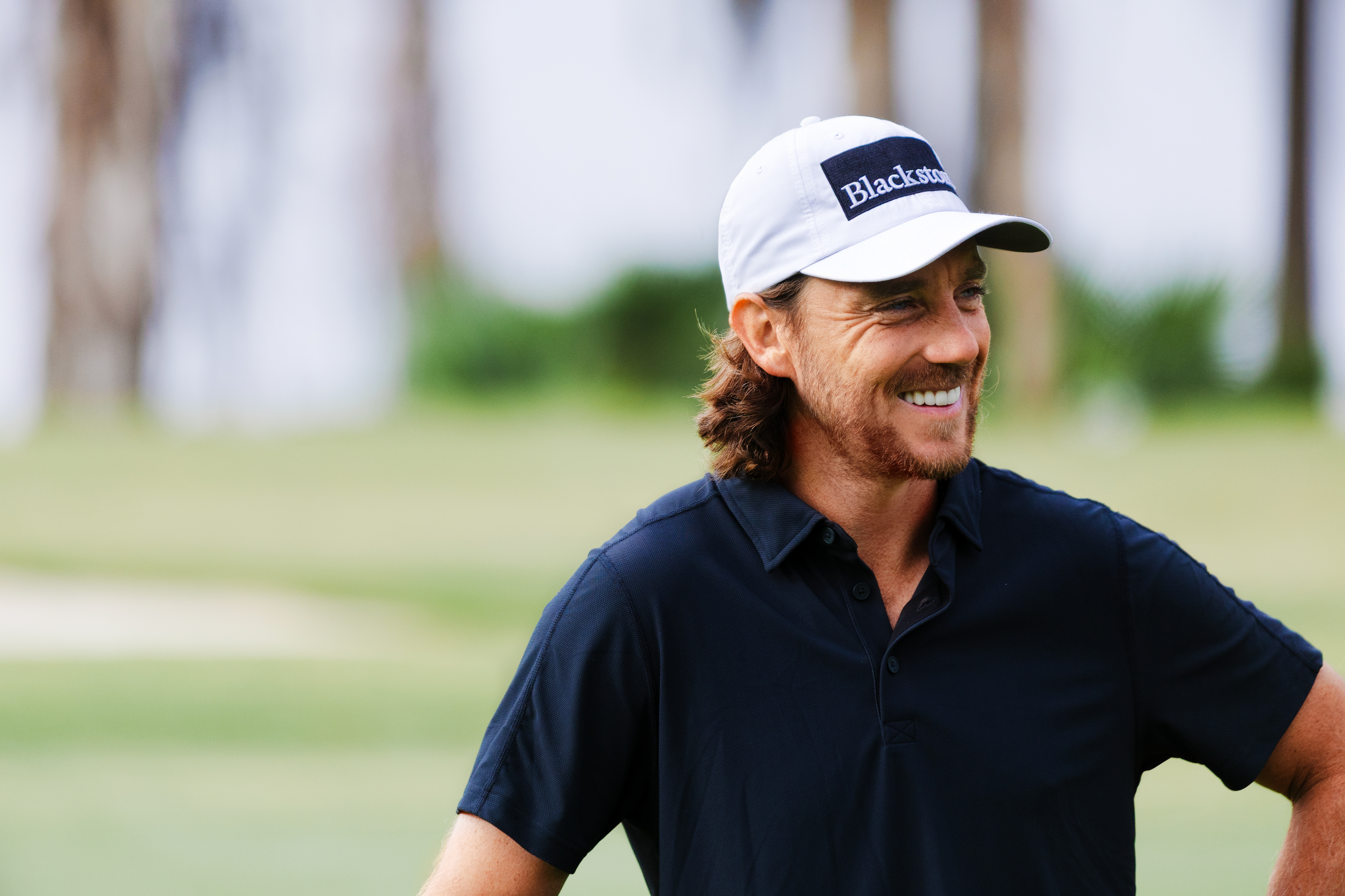 Tommy Fleetwood smiles looking into the distance