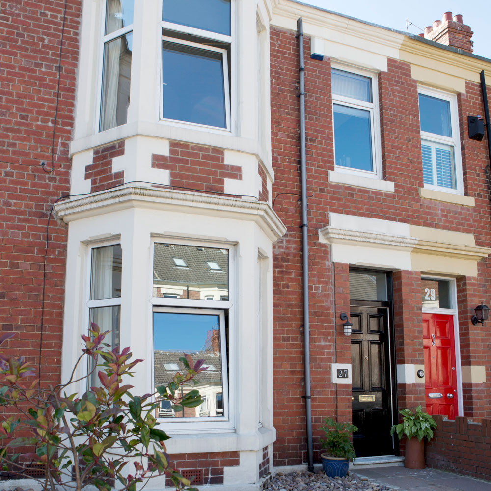 Terraced house with a black front door and planters in front of it