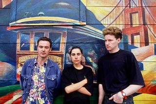 PJ Harvey and band in 1993 standing against a brightly painted wall
