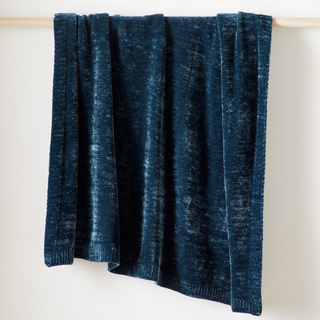 A navy blue chenille throw blanket hanging from a rack