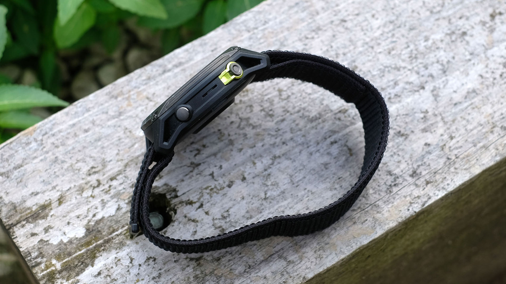 A picture of the Garmin Enduro 3 smartwatch sitting on its side on top of a wooden plank