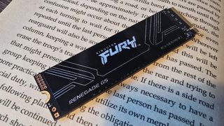 A photo of an 8 TB Kingston Fury Renegade G5 SSD, resting on the open page of a book