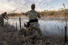 Texas National Guard troop puts up razor wire along the Rio Grande river