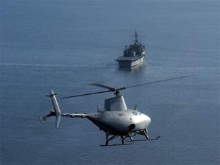 The RQ-8A Fire Scout, a drone helicopter, prepares to land by itself on the amphibious transport dock ship USS Nashville.