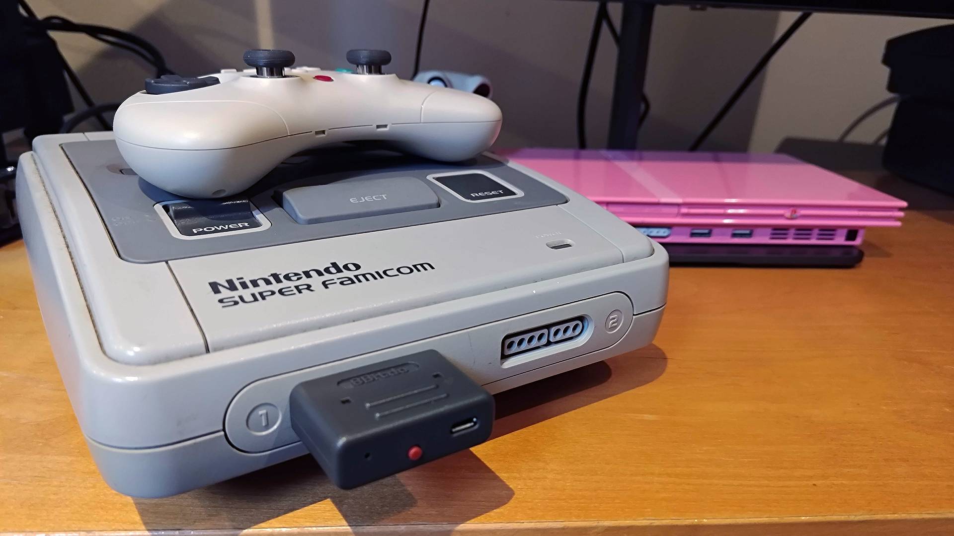 8Bitdo Retro Receiver plugged into Super Famicom with Gulikit Elves 2 Pro sitting on top of console.