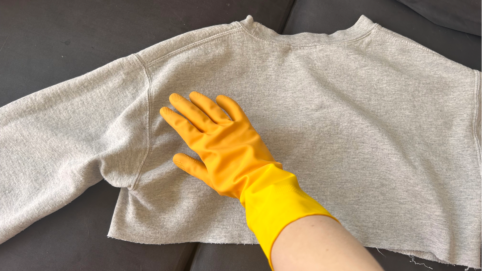 Megan's hand in a rubber glove, rubbing against a gray sweatshirt