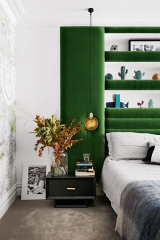 Master bedroom with larger green velvet headboard with built in shelving and pendant lights