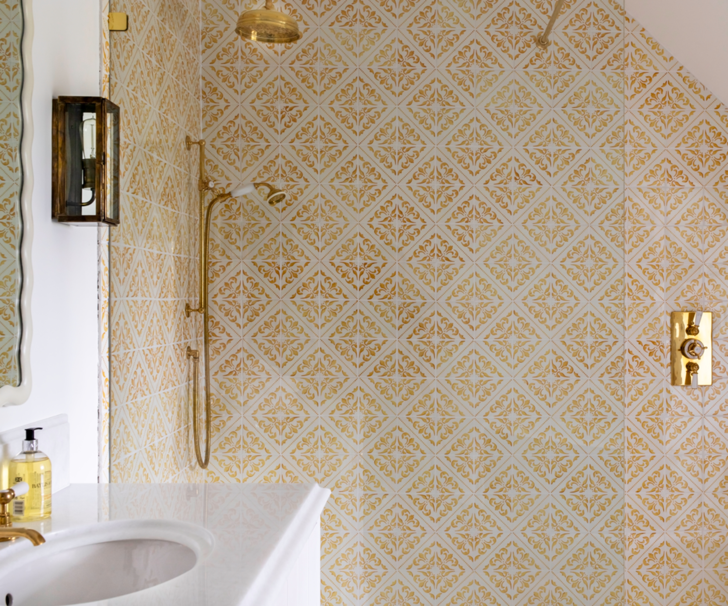 yellow and white patterned tiles in shower area with gold fittings